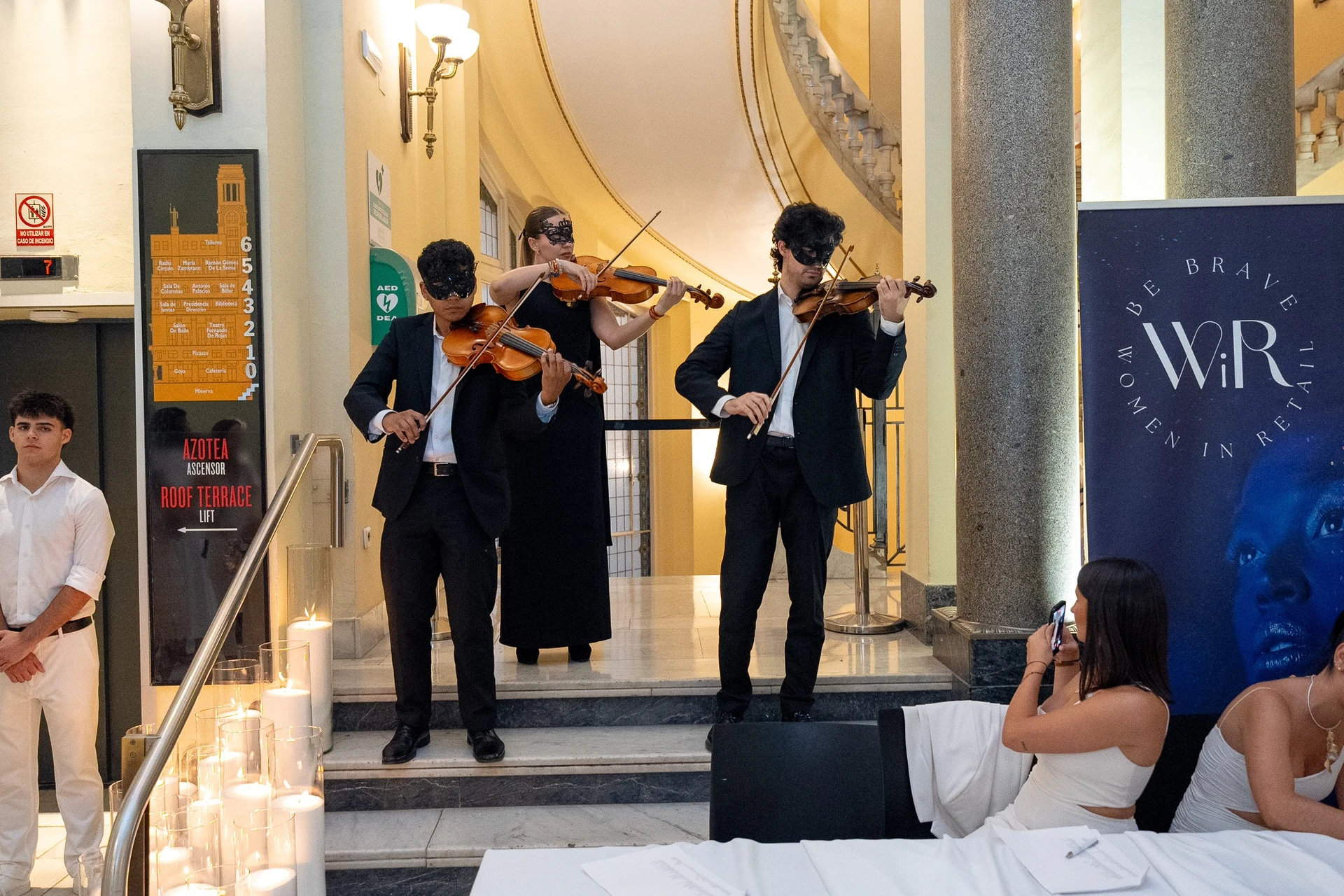 Tres violinistas con máscaras reciben a los invitados de Women in Retail
