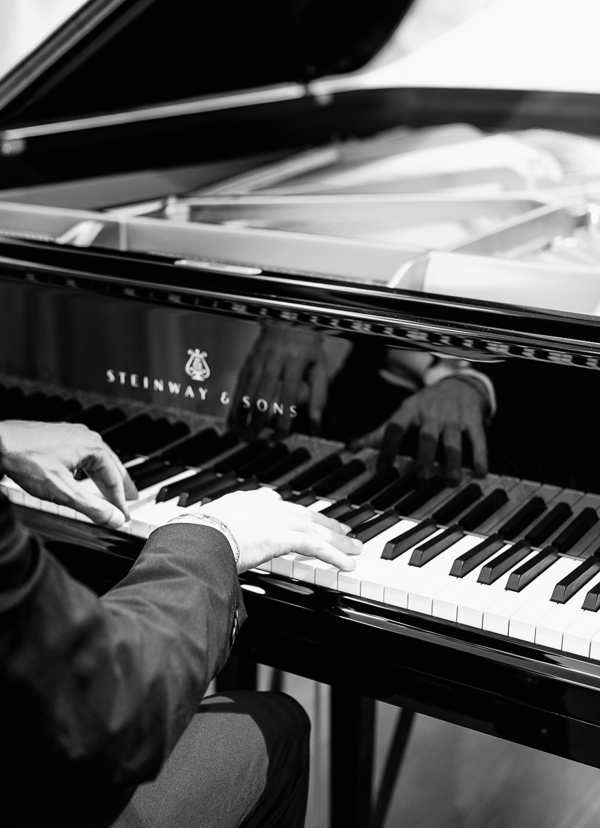 Plano detalle de manos tocando piano elegante y sofisticado durante evento, música en vivo acompañando la celebración.