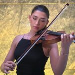 Violinista profesional tocando música en vivo en boda o evento elegante, fondo minimalista que resalta la sofisticación.