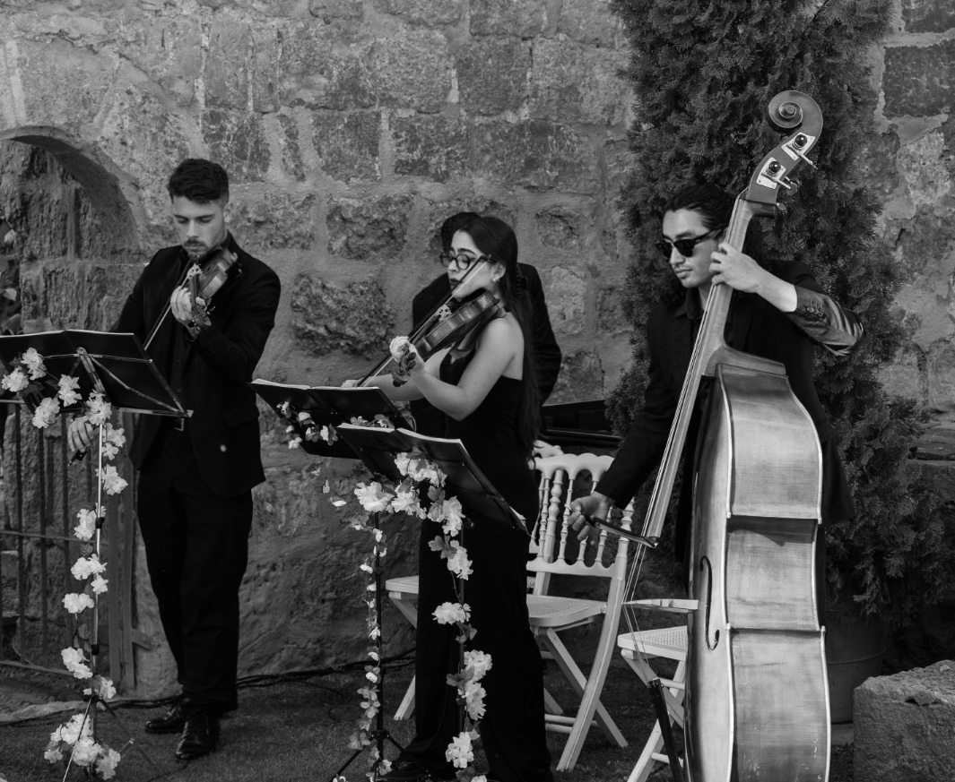Trío de cuerda elegante y moderno en coctel, vestidos en blanco y negro, interpretando canciones de Taylor Swift en evento sofisticado.